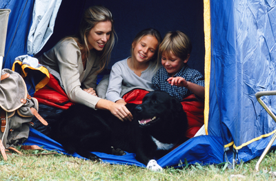 Family in a tent with a large black dog